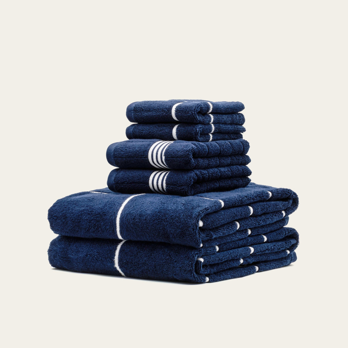 Neatly stacked navy cotton towels with white stripe bands