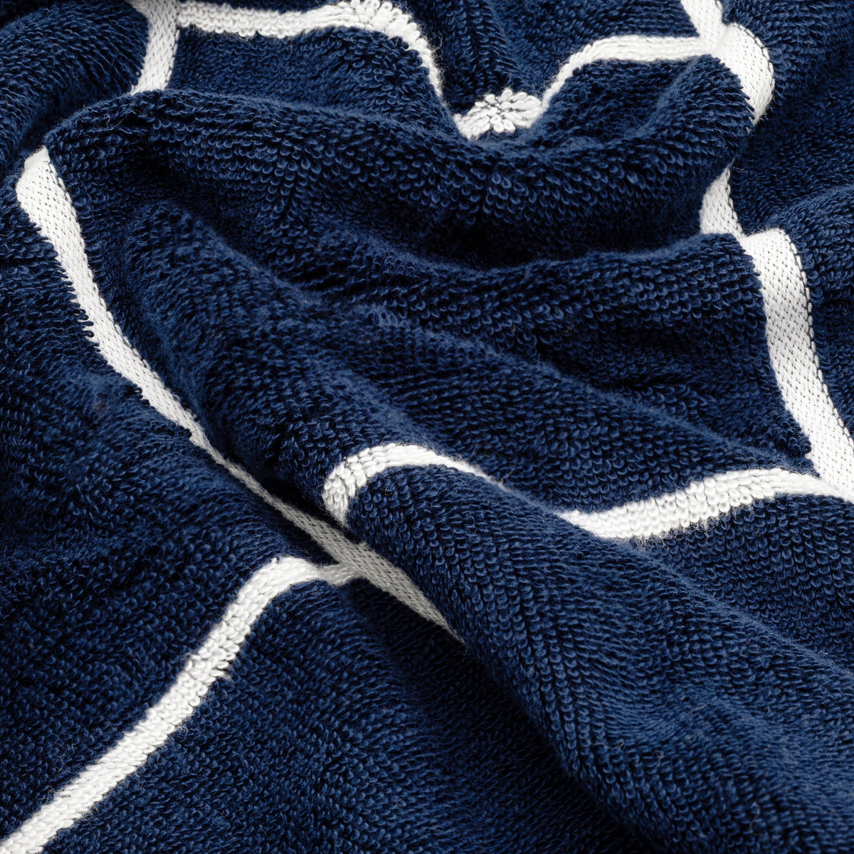 Navy terry cotton towel with white grid stripe pattern, close-up texture