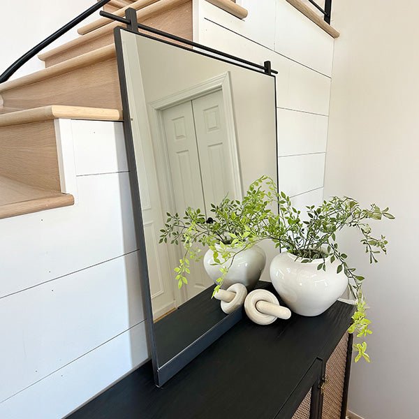 Rectangular wall mirror with black metal frame and clear glass panel