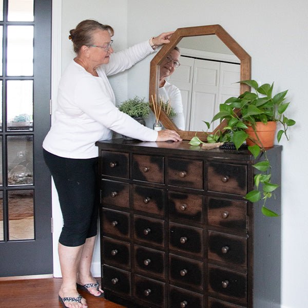 Octagon wood frame mirror held by person, warm brown octagonal frame and clear glass