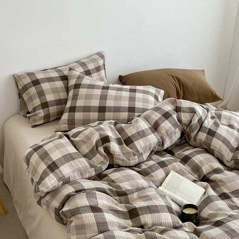 Brown-and-gray plaid duvet cover set with pillow shams and folded blankets on the bed.