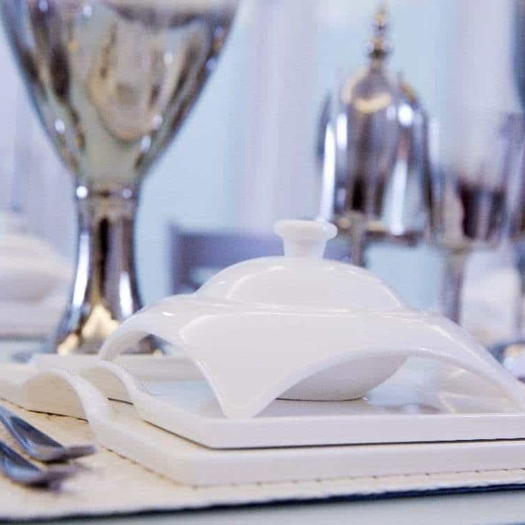White porcelain covered serving dish with square tray and stacked plates