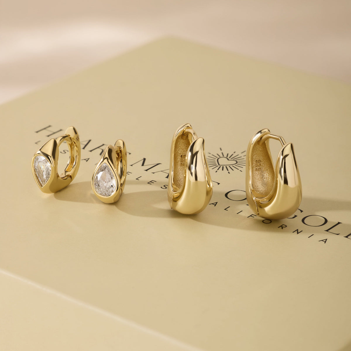 Wavy gold hoop earrings set with clear cubic zirconia stones, assorted sizes