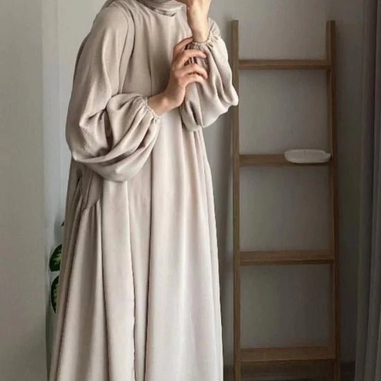 Light beige pullover abaya with hood and lantern sleeves; loose pleated fit