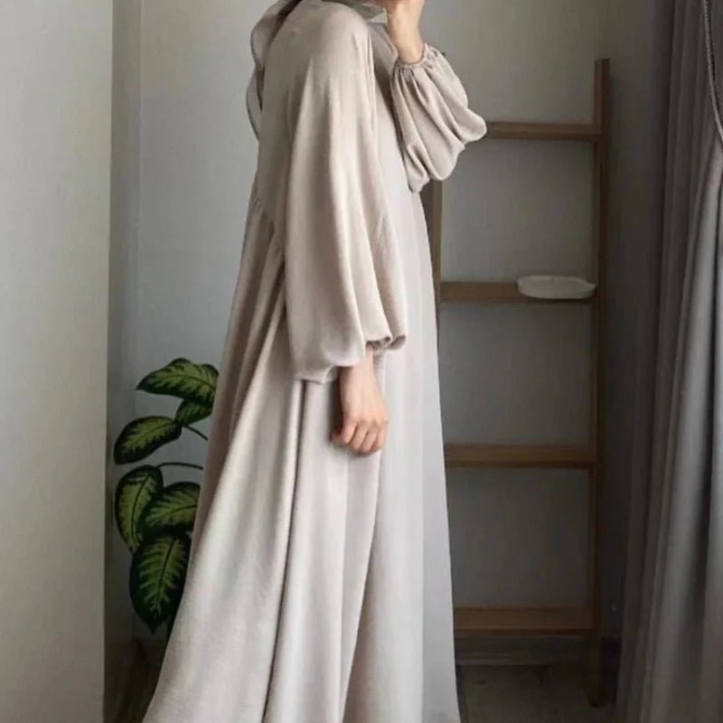 Beige abaya side view with gathered lantern sleeves and long, flowing hem