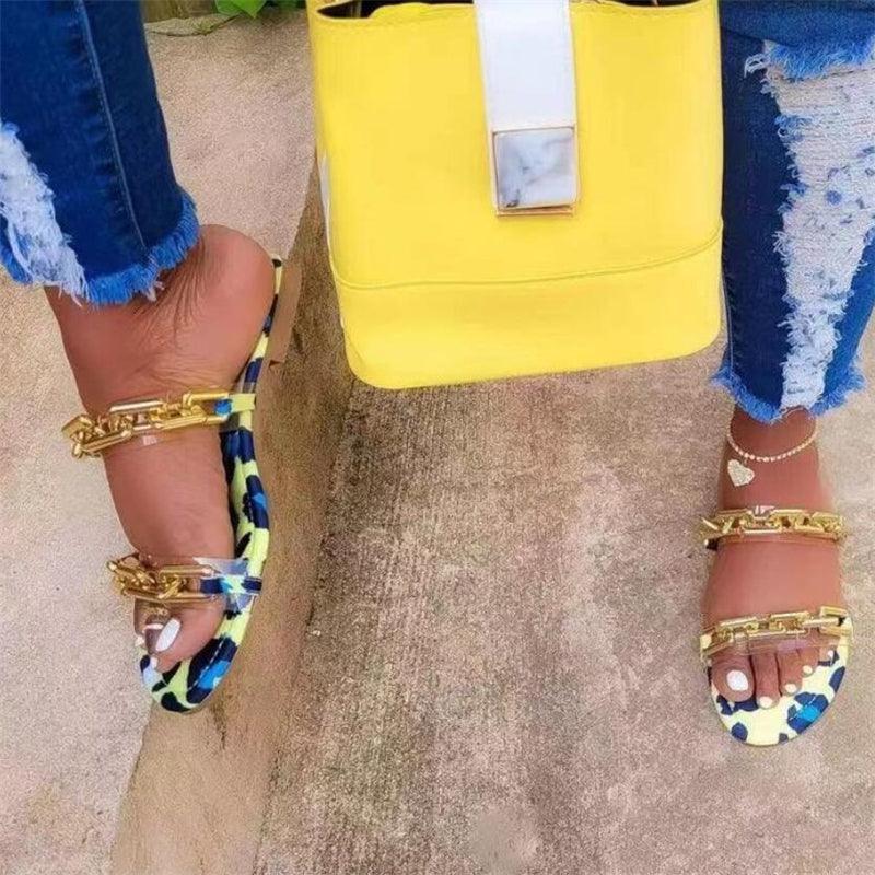 Blue patterned open-toe flat slide sandals with gold chain straps and ankle bracelet