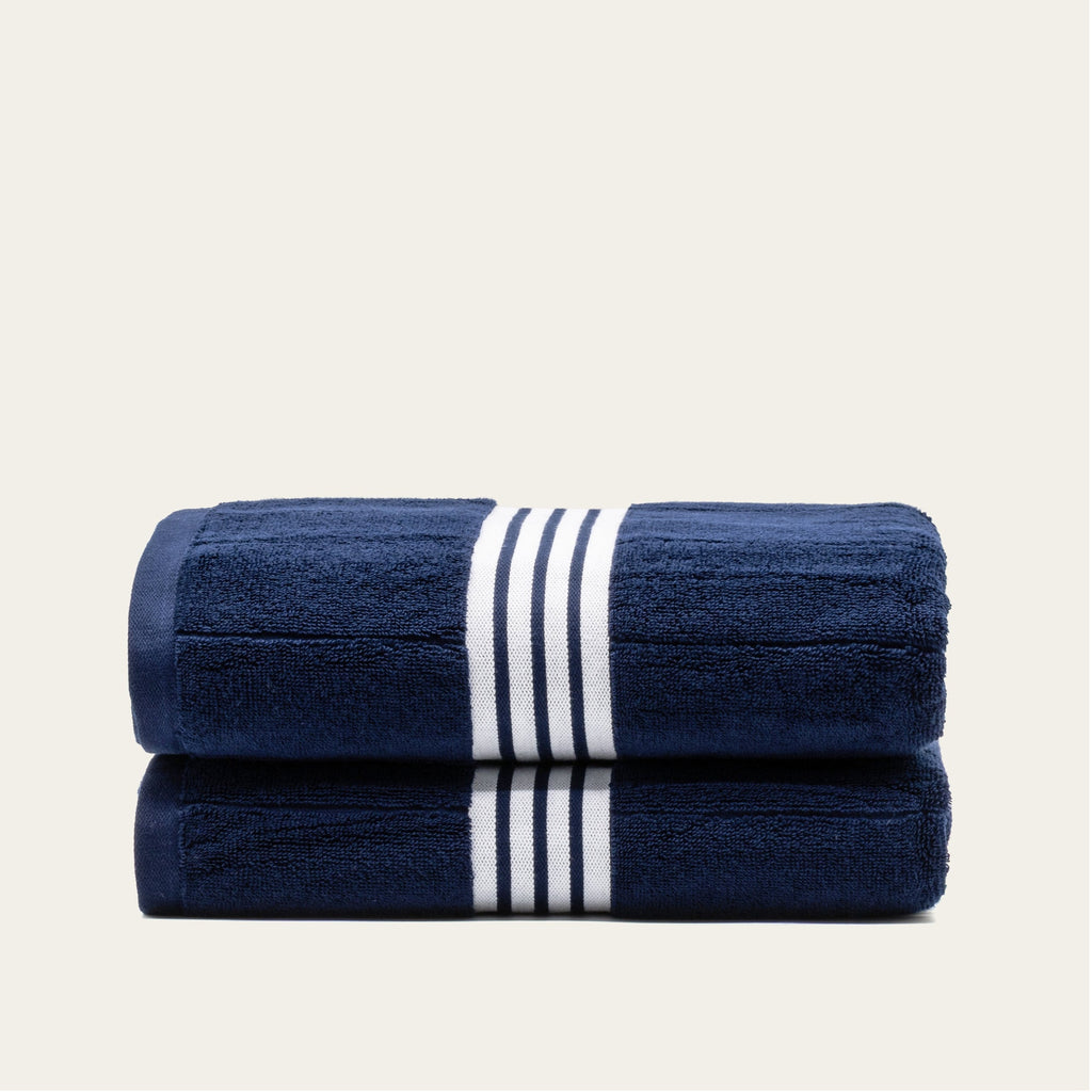 Two folded navy cotton towels with white striped bands, neatly stacked