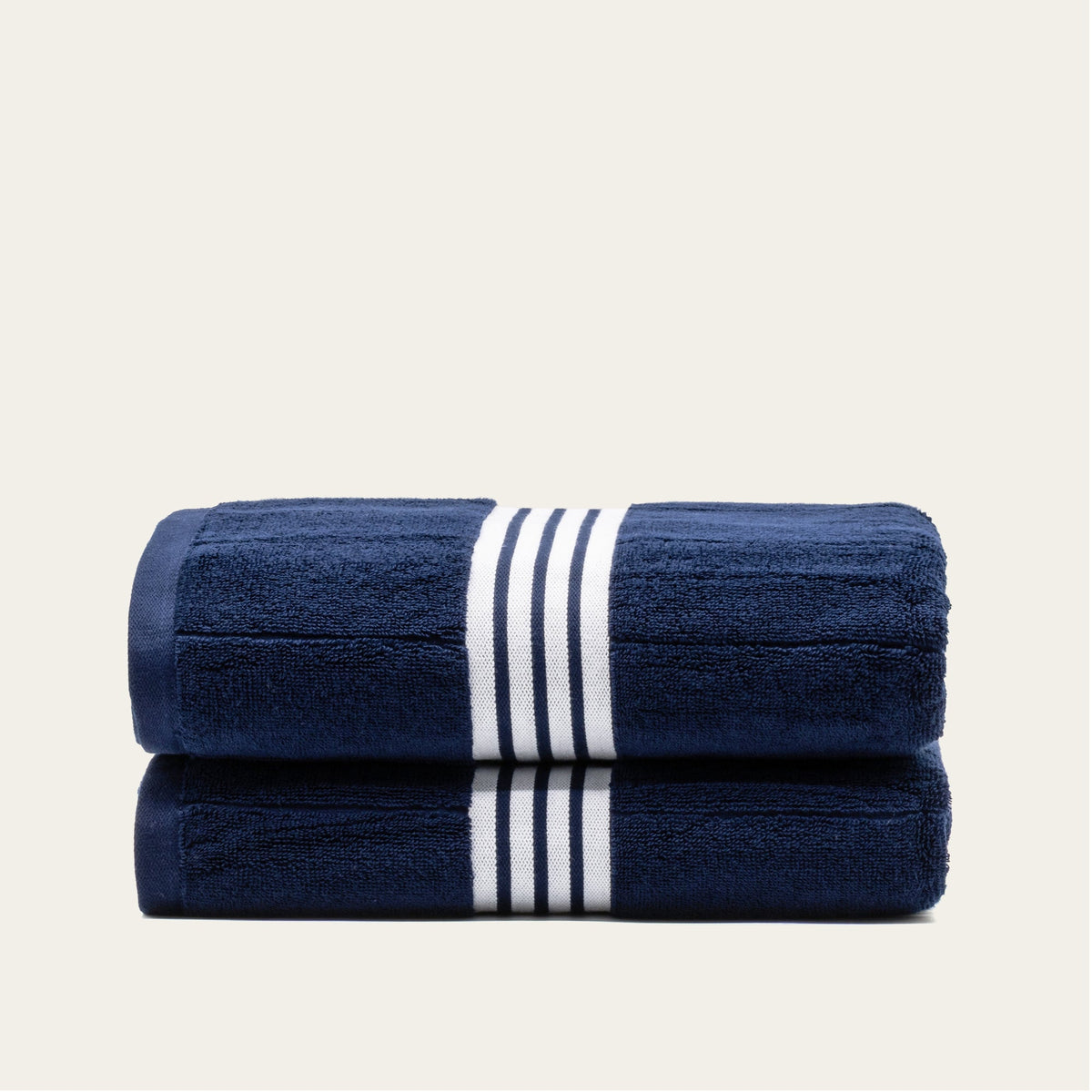 Two folded navy cotton towels with white striped bands, neatly stacked