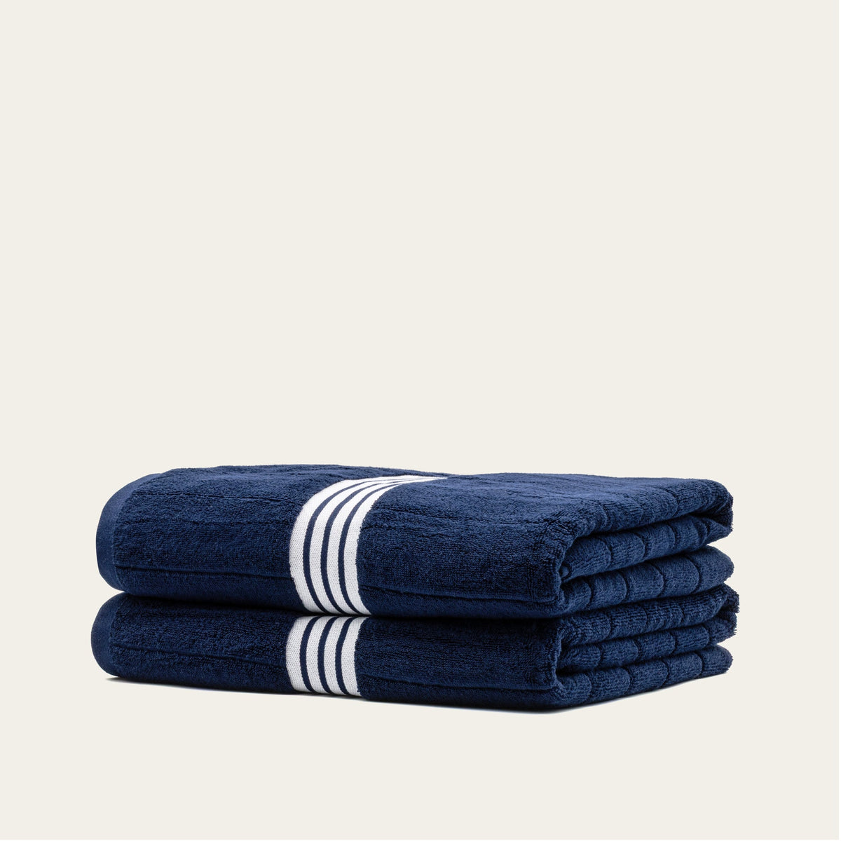 Rolled navy cotton towels with white striped bands, stacked as a towel set