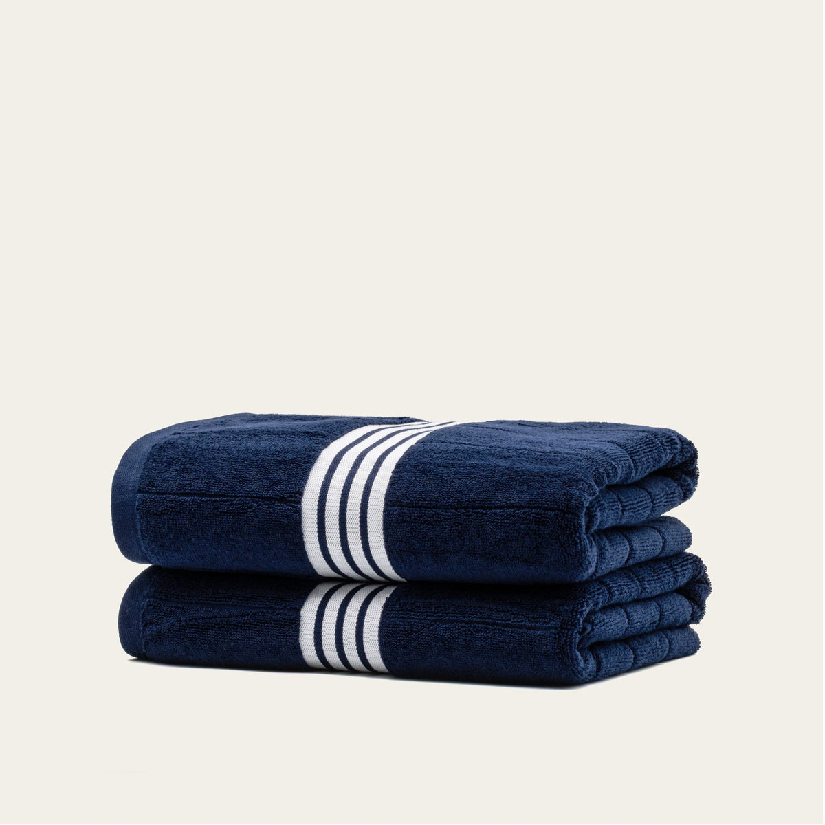 Stacked navy cotton towels with white striped bands, folded for a compact set