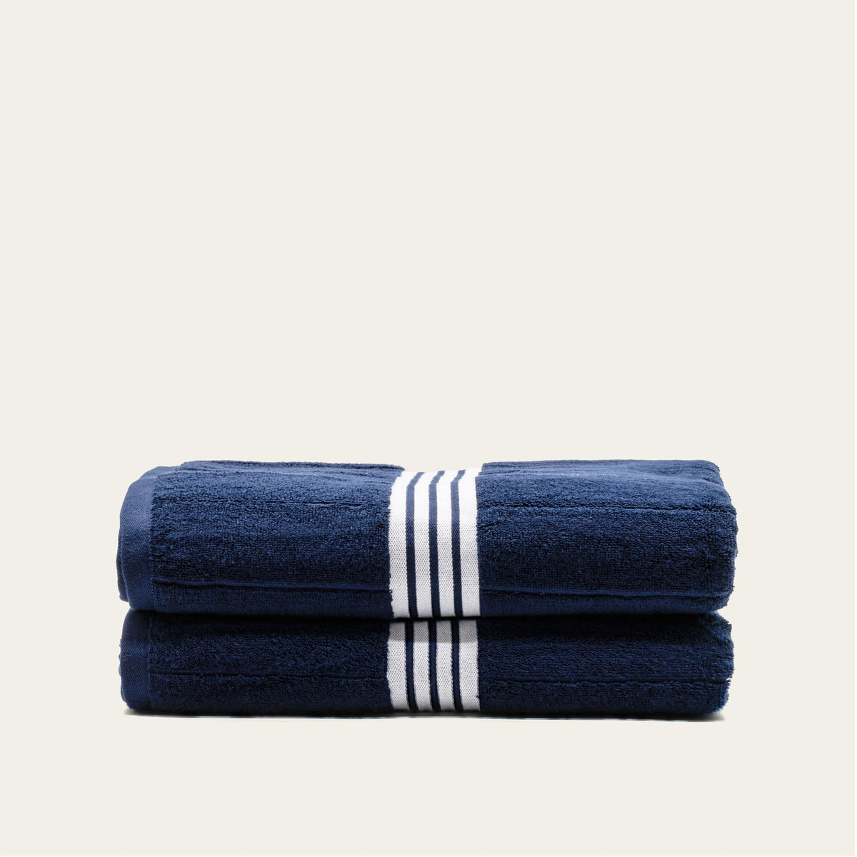 Two-layer folded navy cotton towels with white striped bands, shown side by side