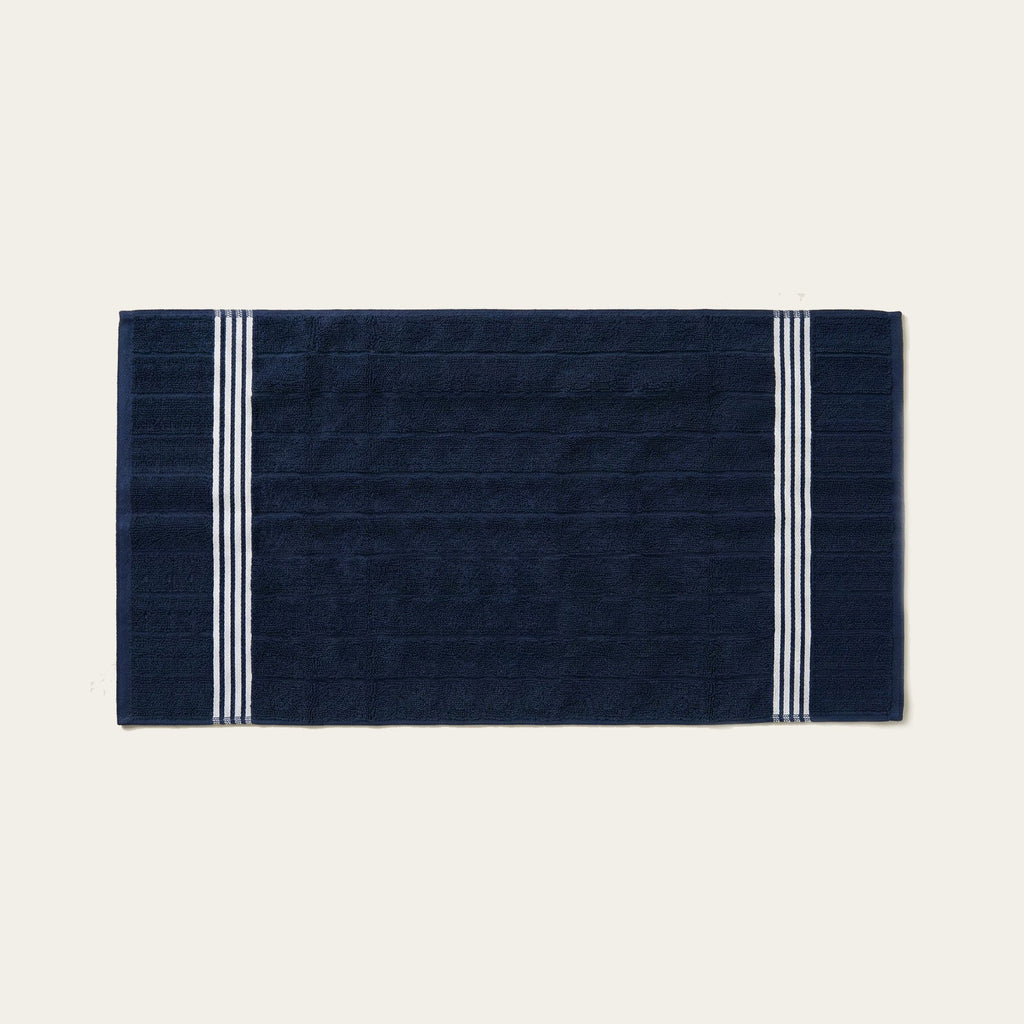 Navy cotton bath sheet with white striped border, flat folded