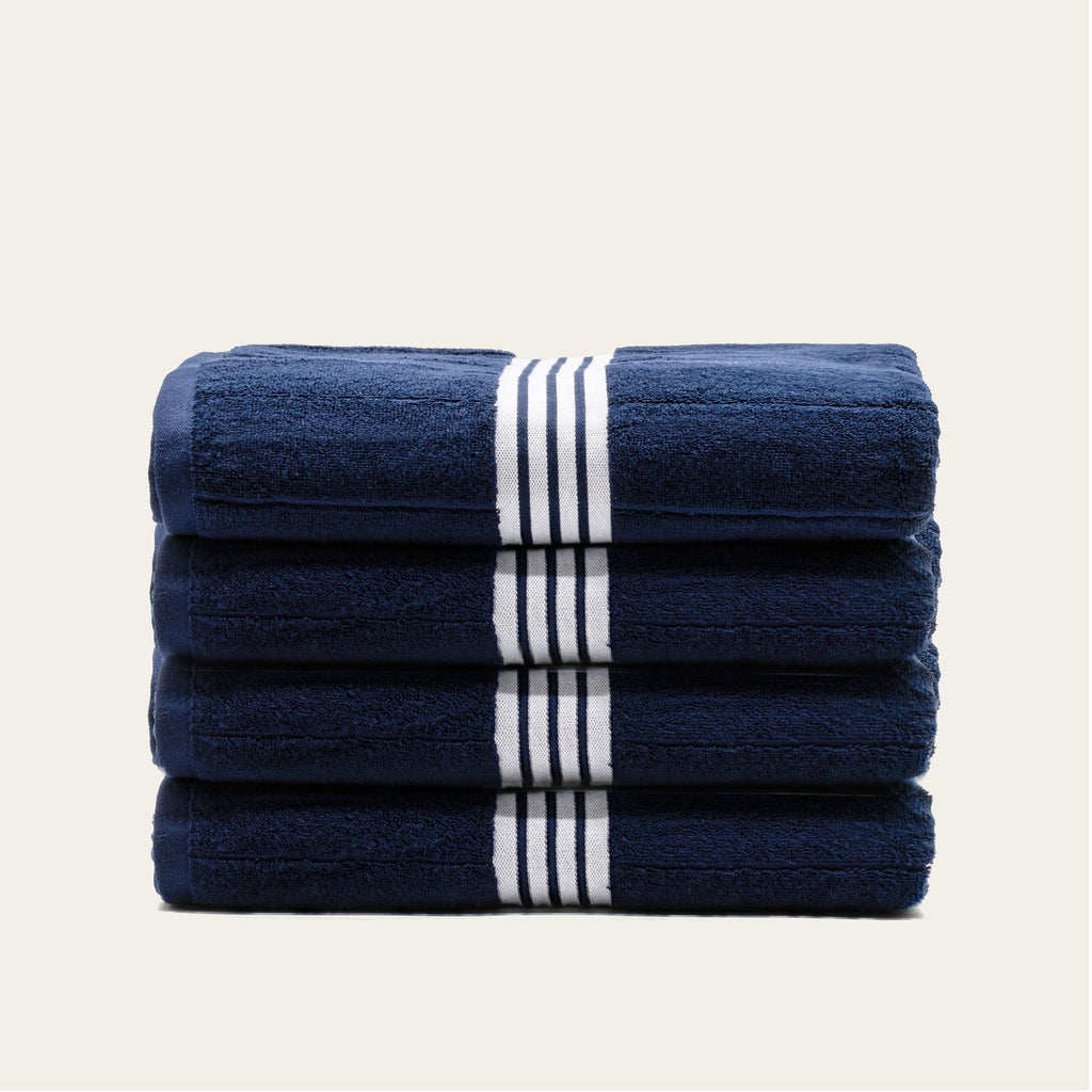 Stack of navy bath towels with white striped bands, folded neatly