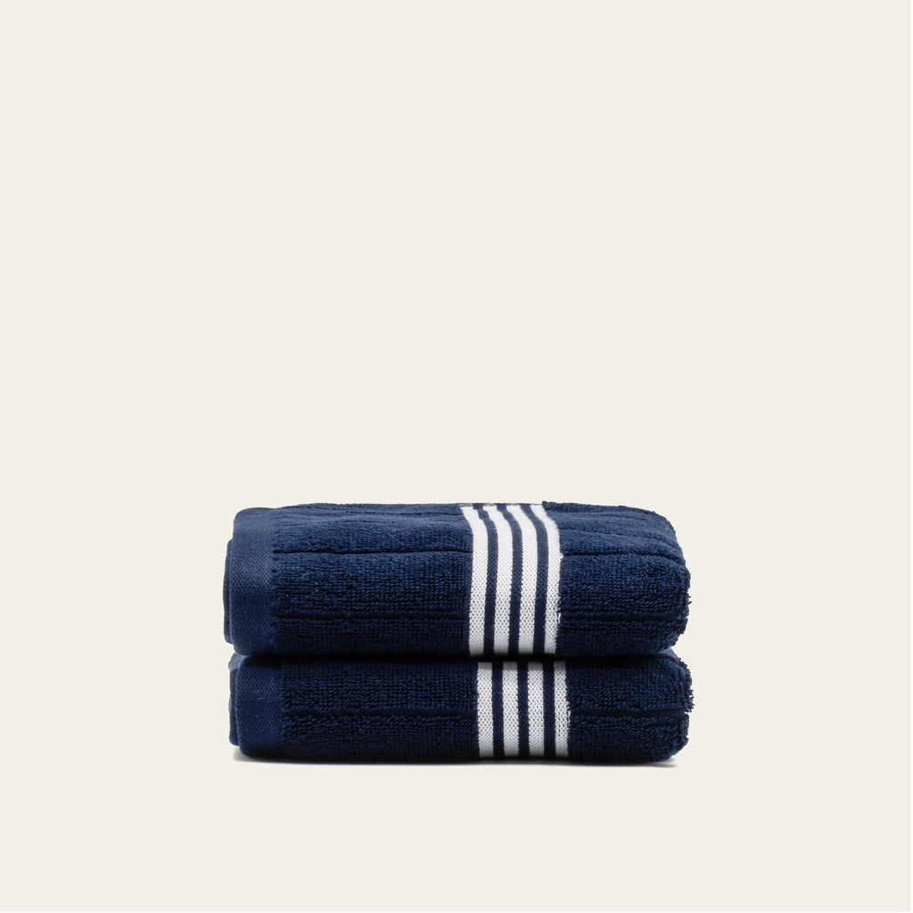 Folded navy cotton towels with white striped bands, shown as a two-towel stack