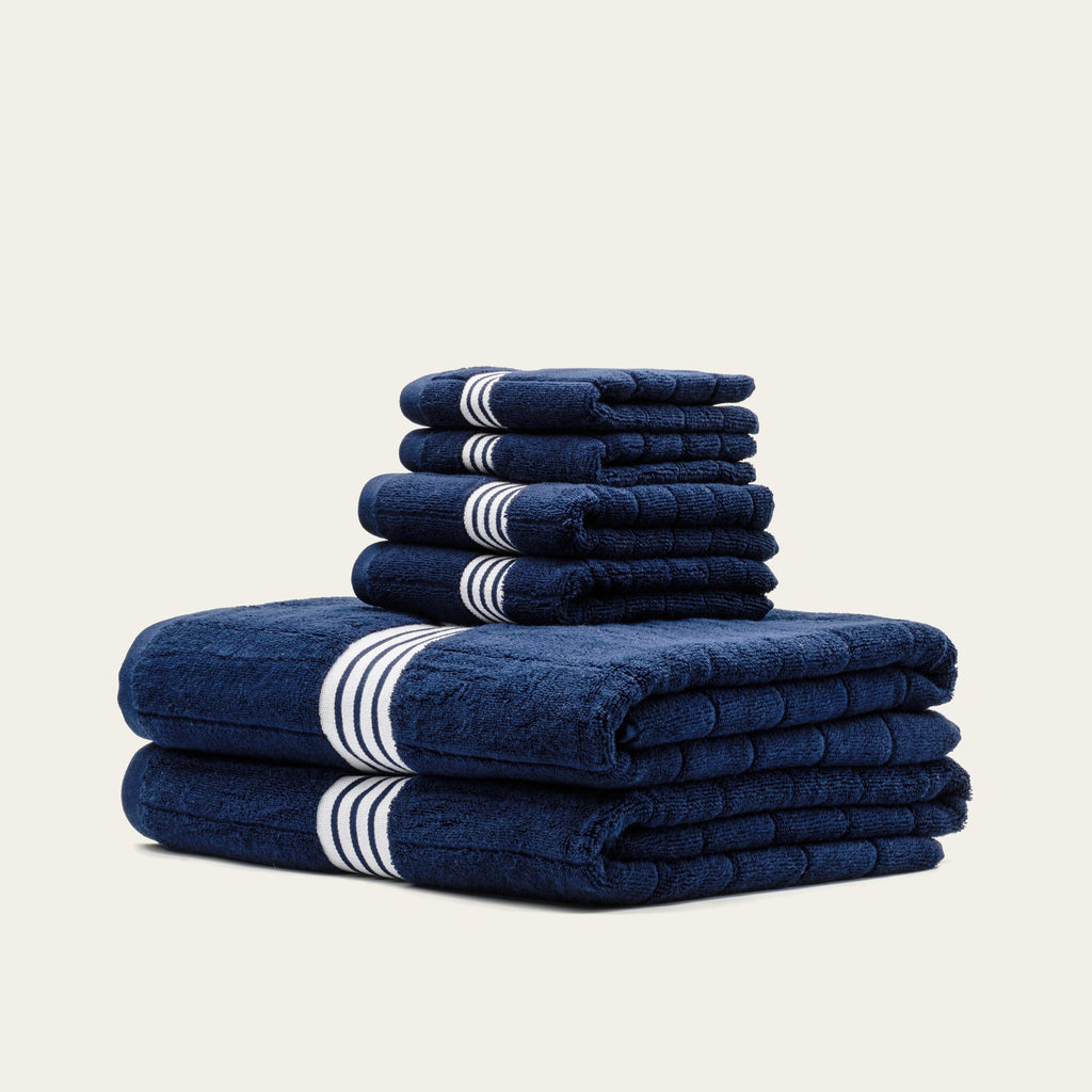 Tall stack of navy towels with white striped bands, folded into a set
