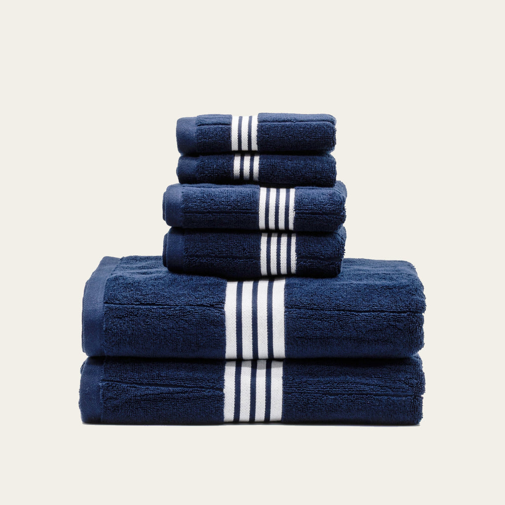 Navy towels folded with white striped bands, with a larger top towel
