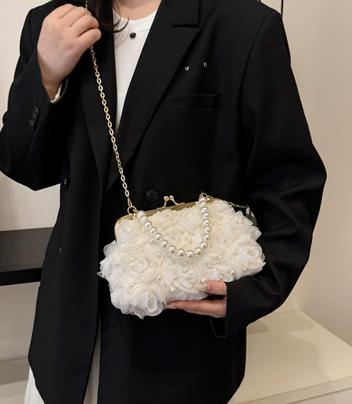 White pearl-and-lace mini clutch crossbody, worn with long gold chain strap
