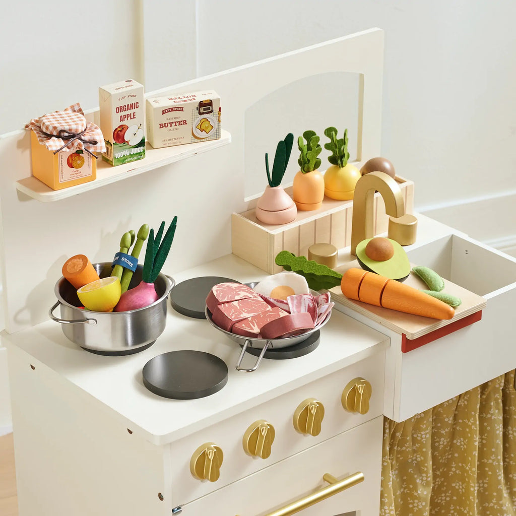 Toy kitchen counter display with sliced meat, seafood, and produce play accessories