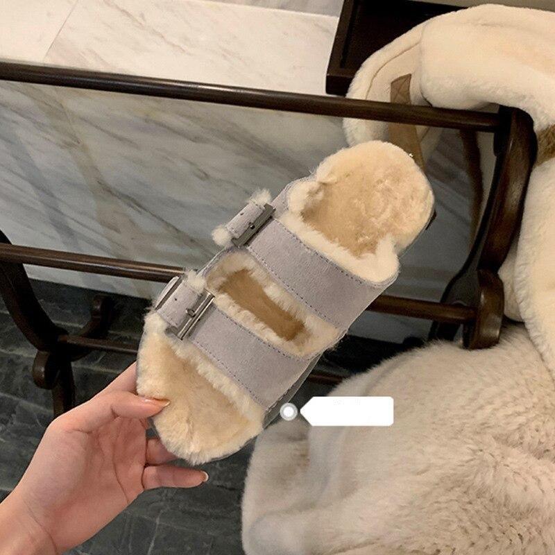 Light gray double-buckle faux-fur slippers held up, plush lining and buckles visible
