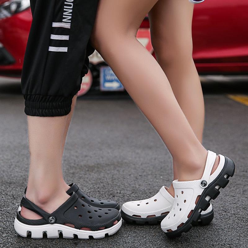 Pair of black and white perforated clogs with adjustable heel straps