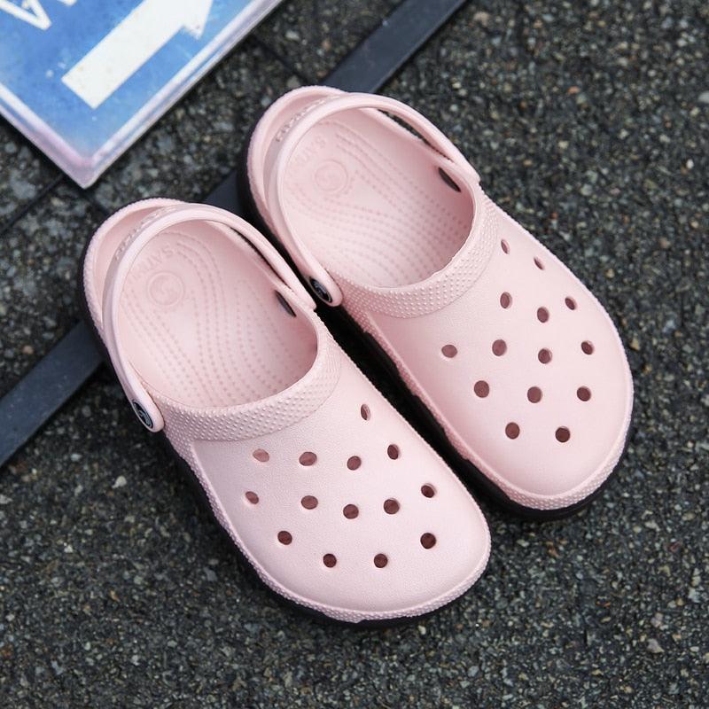 Light pink perforated clogs with black outsole and adjustable side strap