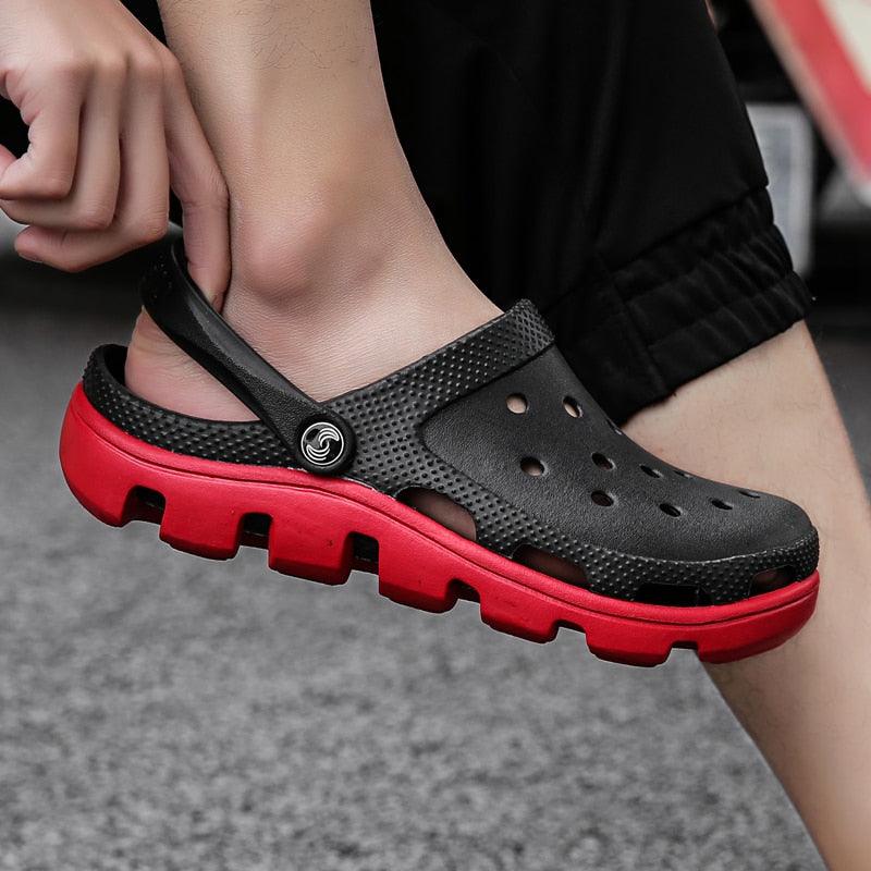 Black mesh clogs with red outsole, perforated upper and adjustable back strap