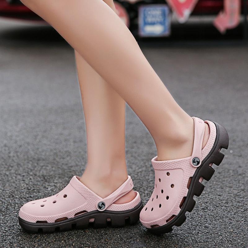 Blush pink perforated clogs with black outsole and adjustable back strap