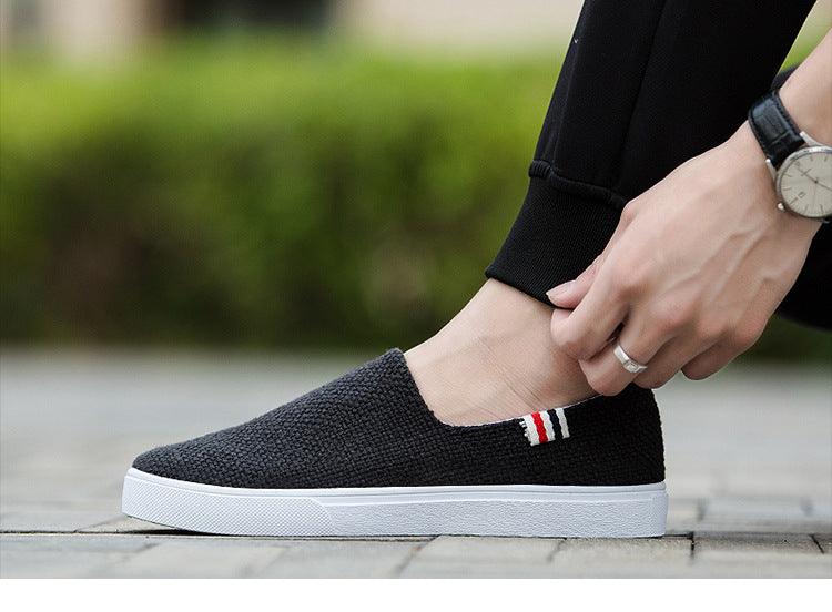 Black canvas slip-on sneakers with white sole and flag stripe detail