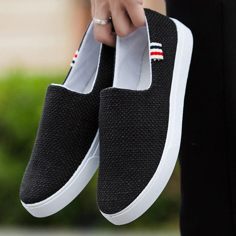 Black canvas slip-on sneakers with white rubber sole and side flag detail