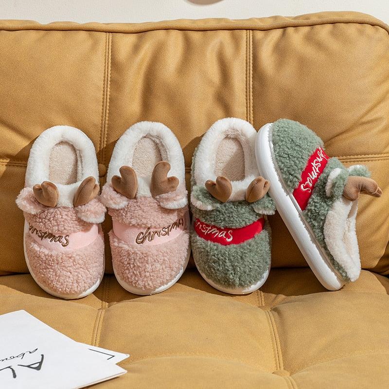 Pink plush deer slippers with antler applique and “Christmas” script on the front