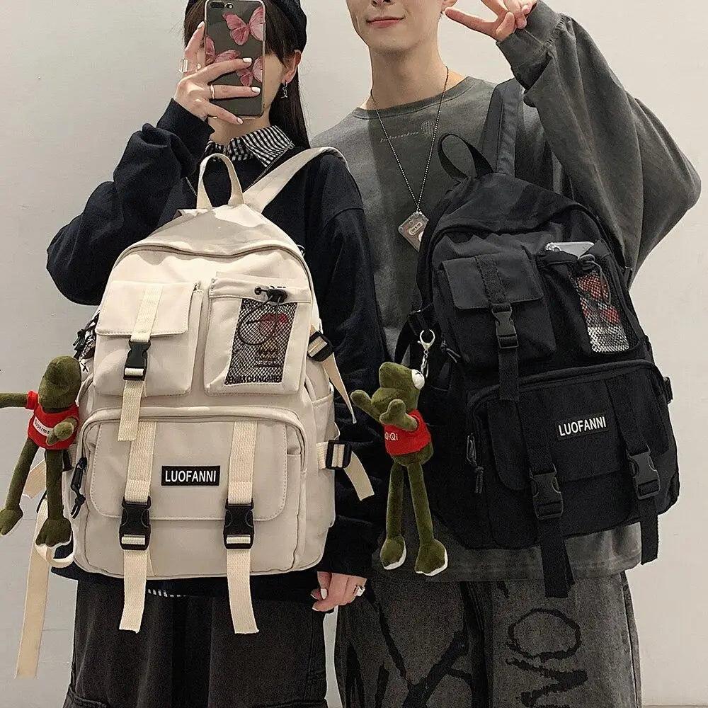 Two student backpacks, white and black, with front pockets, straps, and mesh details