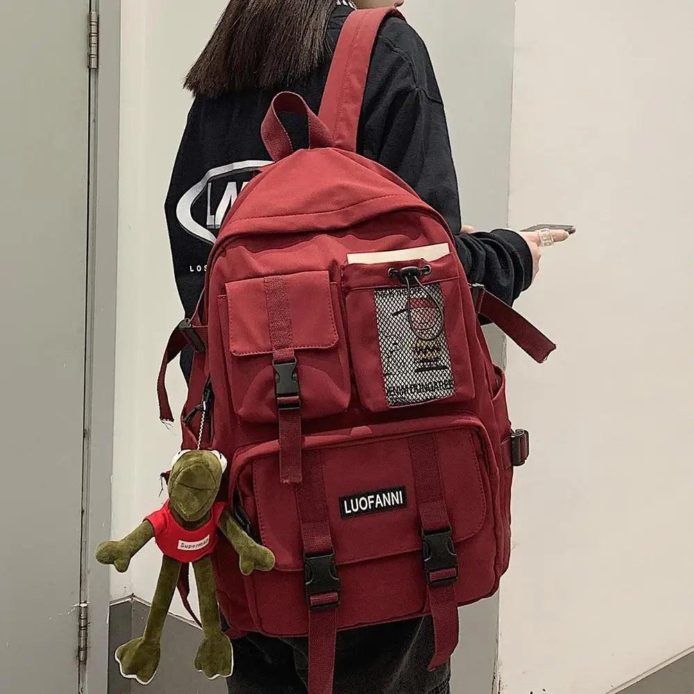 Red nylon backpack with front pockets, web straps, and a mesh side panel