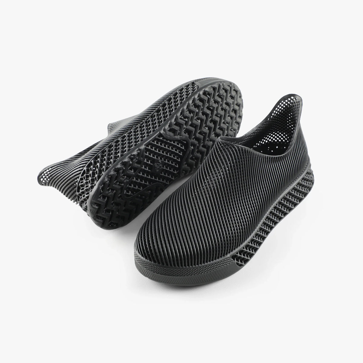 Black 3D printed slip-on sneakers shown with treaded outsole and ribbed upper