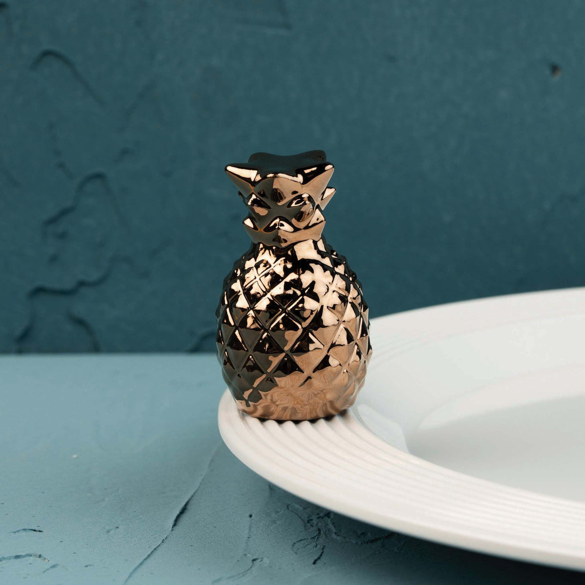 Gold pineapple-shaped decorative holder with black top on white plate