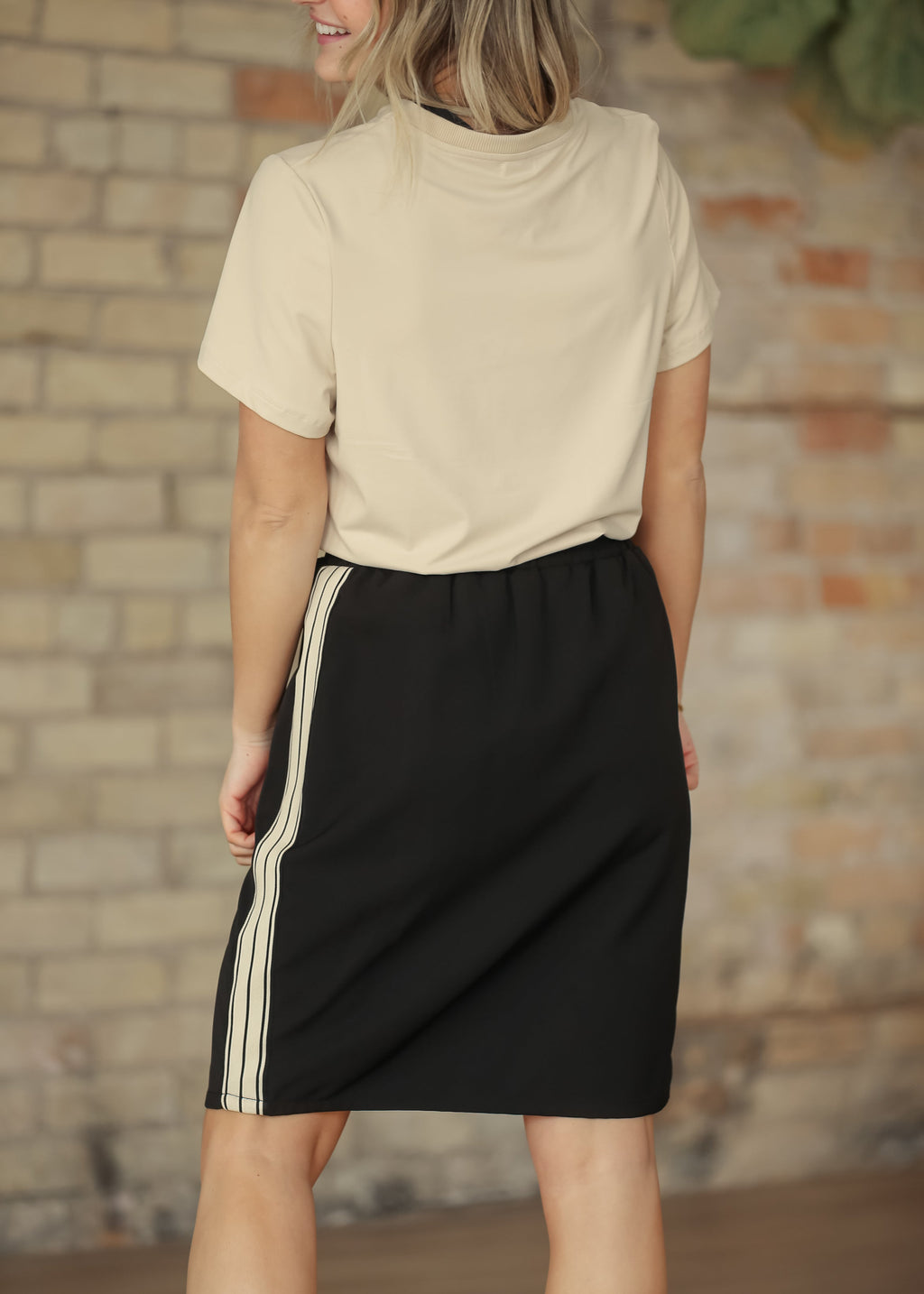 Black mid-rise track skirt with vertical side stripe panels and drawstring elastic waist.