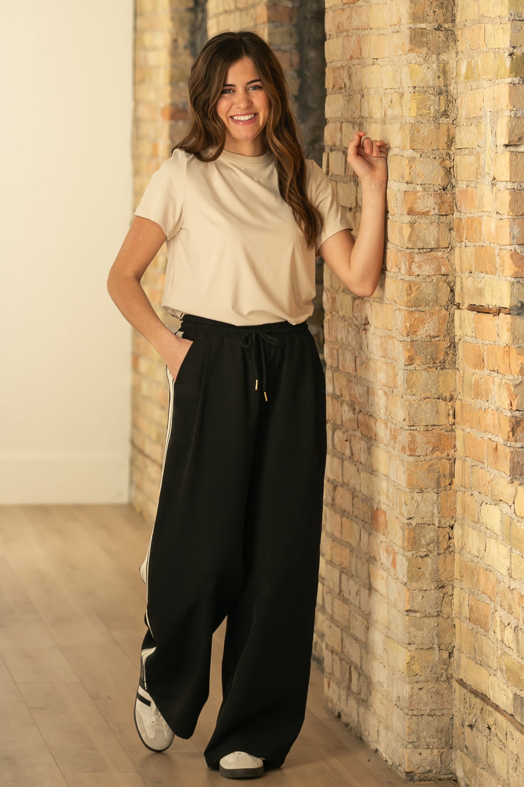 Black wide-leg track pants with white side stripes and drawstring waistband