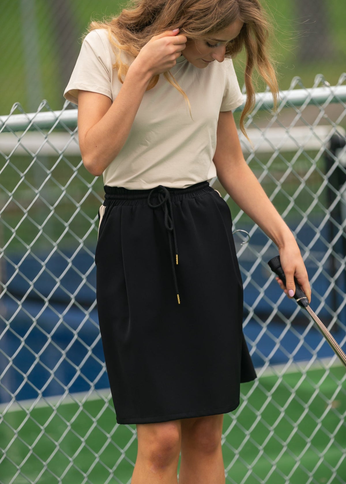 Black mid-rise track skirt with white side stripes and drawstring waist detail