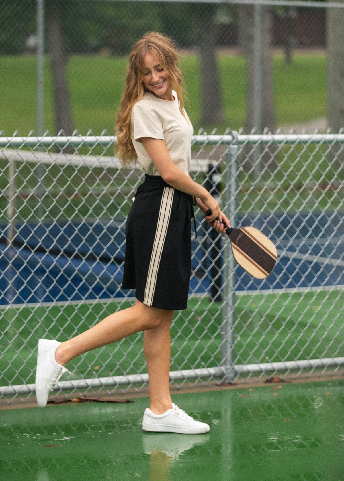 Black mid-rise track skirt with drawstring waist and white side stripe