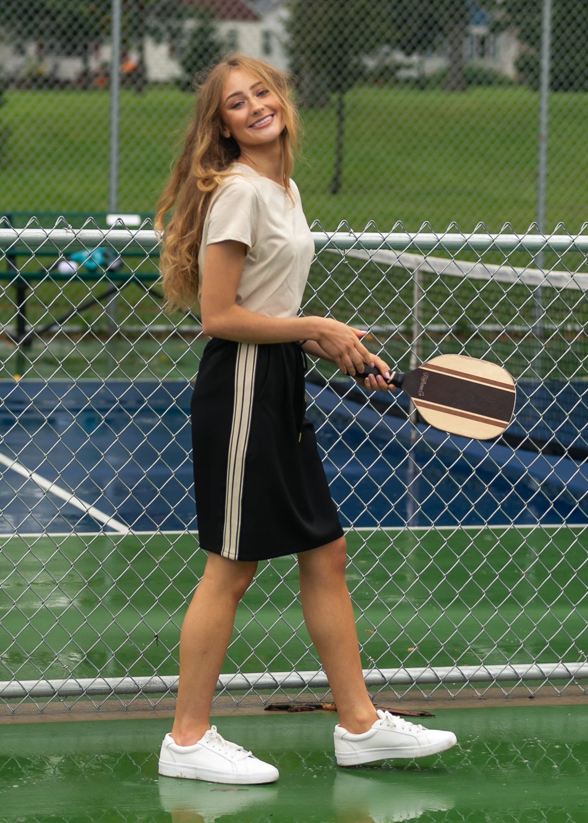 Black mid-rise track skirt with white side stripe accents and drawstring waist