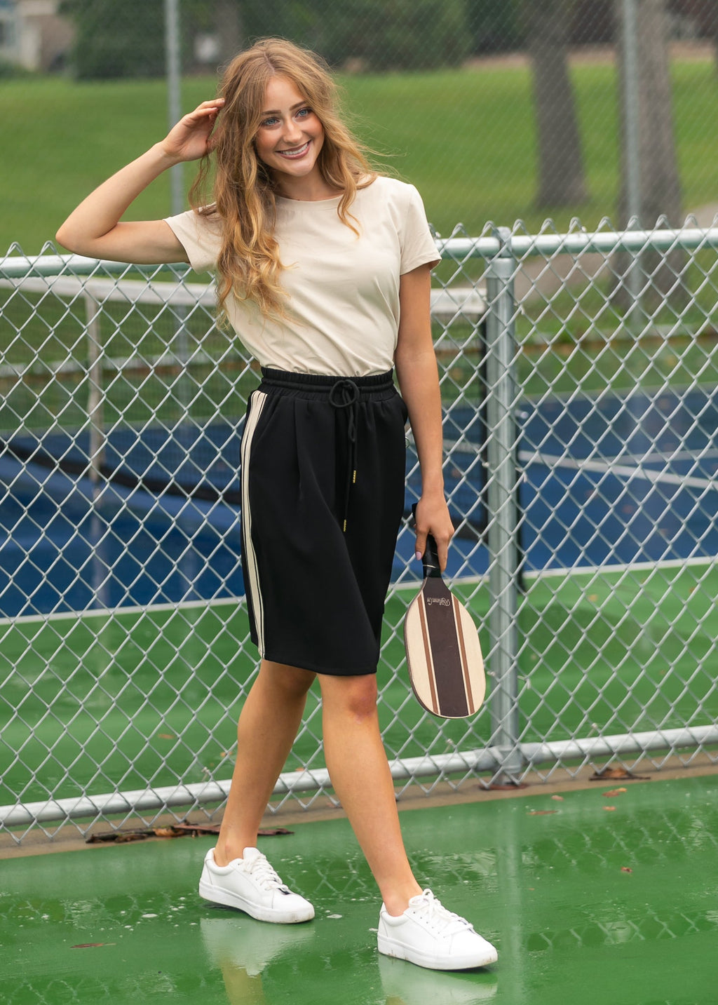 Black mid-rise track skirt with drawstring waist and white side stripe, side view