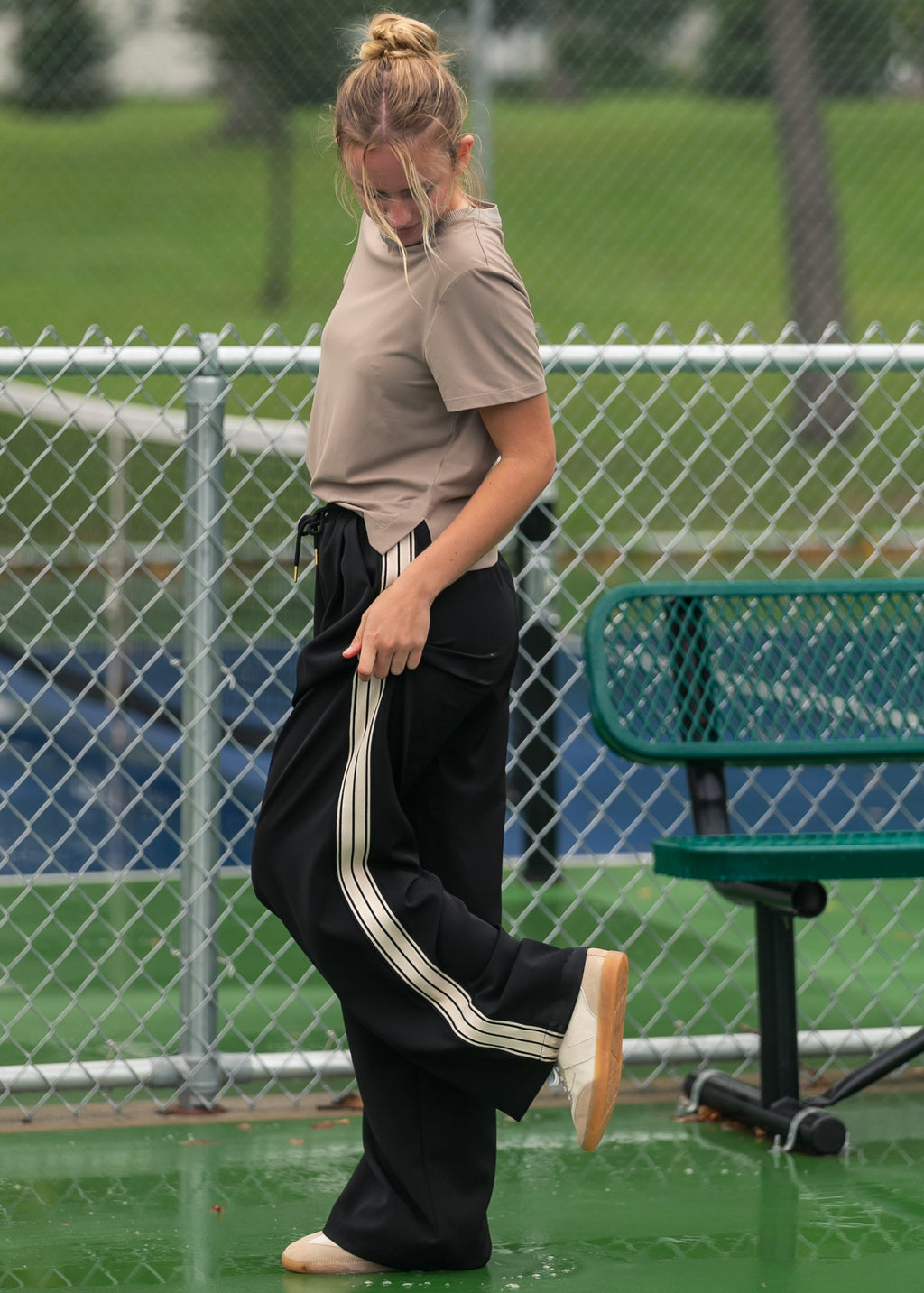 Black wide-leg track pants with white side stripes along the outer legs