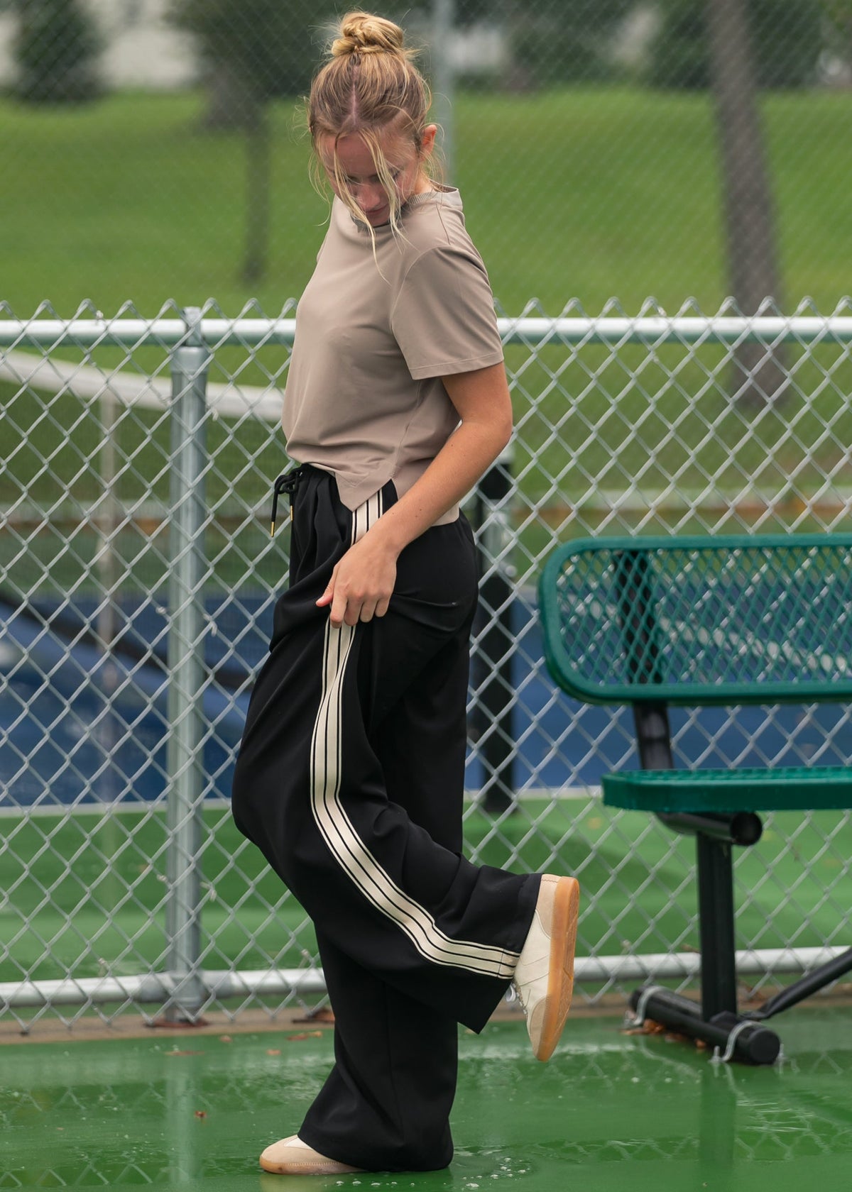 Black wide-leg track pants with white side stripes along the outer legs