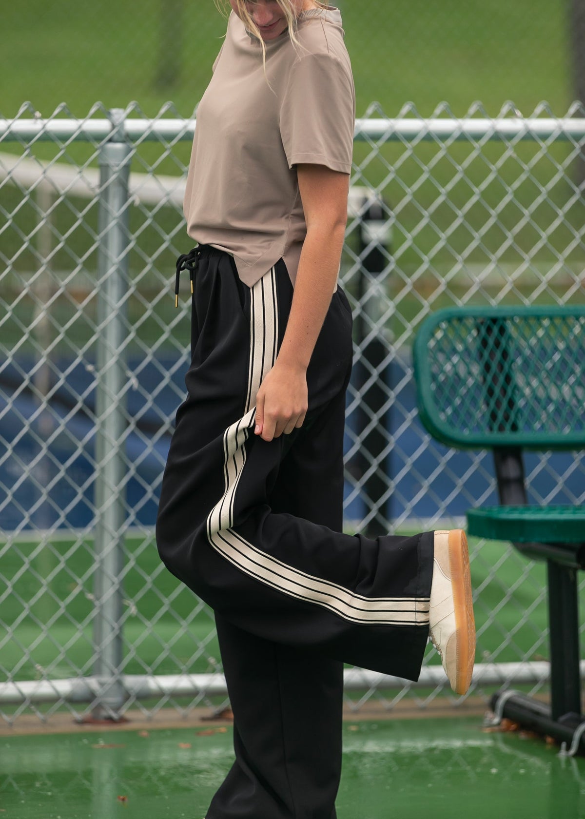 Black wide-leg track pants with white side stripes and relaxed long leg fit