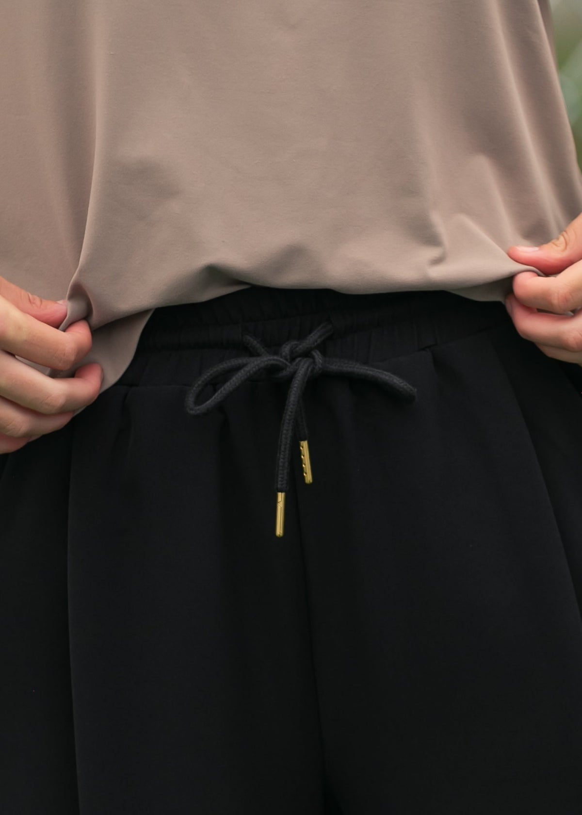 Black track pants waistband with drawstring cord and small gold tips