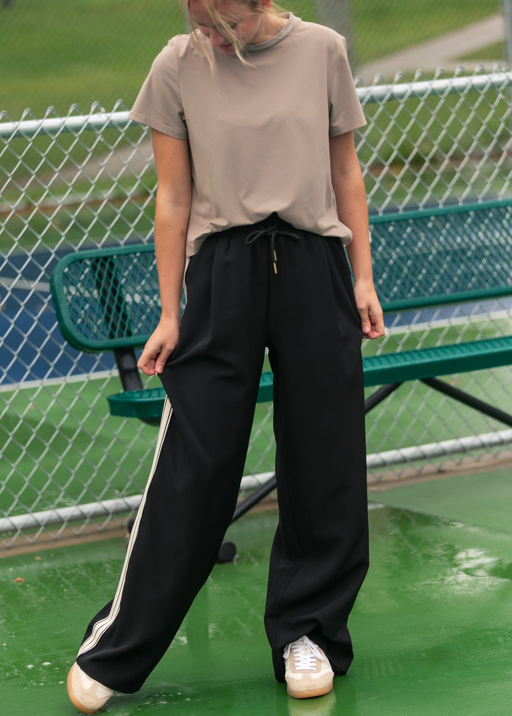 Black wide-leg track pants with white side stripes and drawstring waist on model