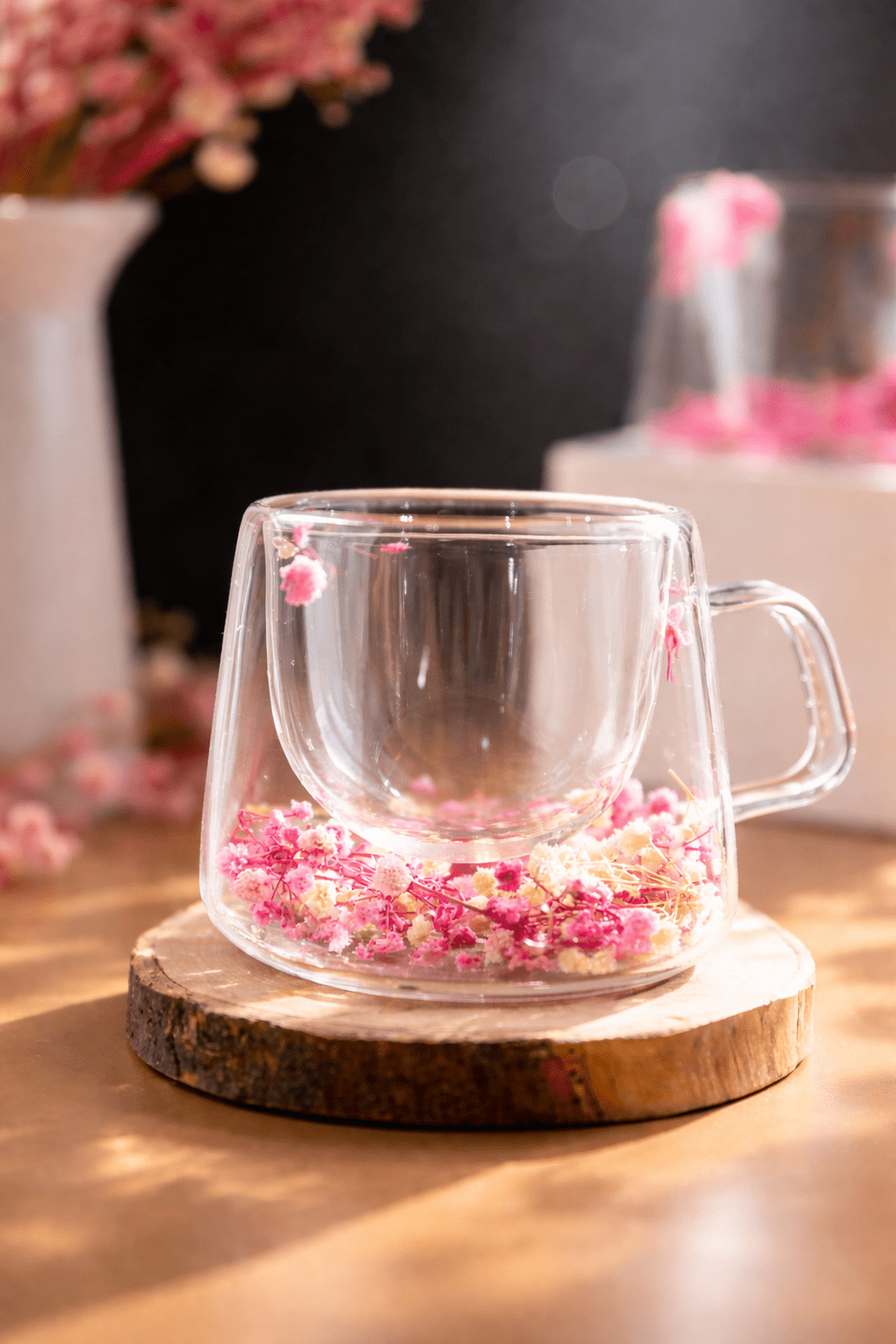 Floral glass mug with pink dried flower petals on clear base, side handle