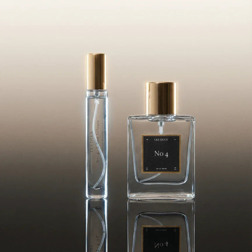 Two glass perfume bottles with gold caps and square bodies