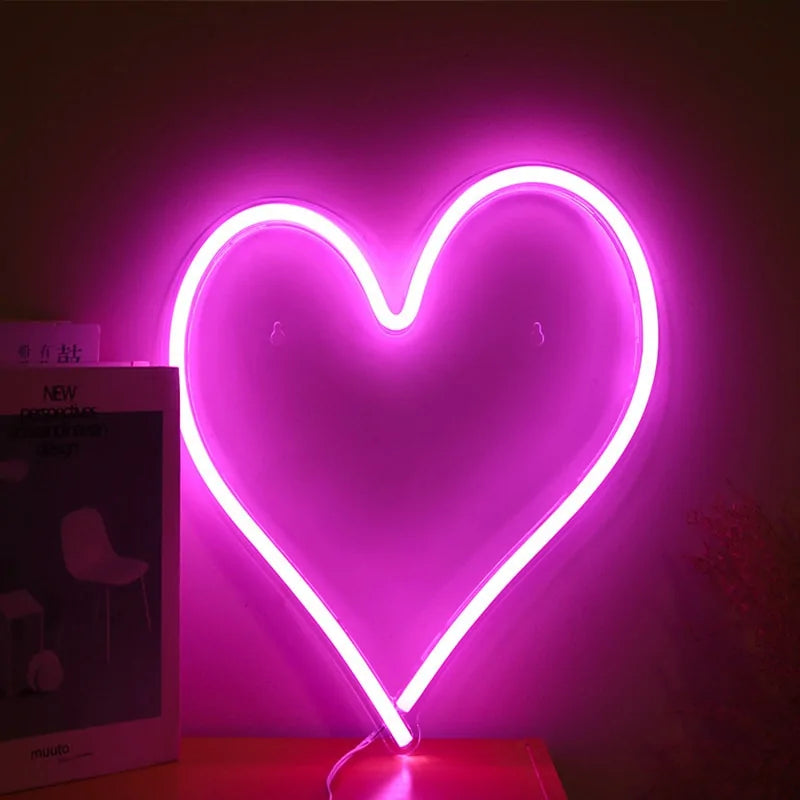 Pink heart neon sign with bright outline, standing on a small base