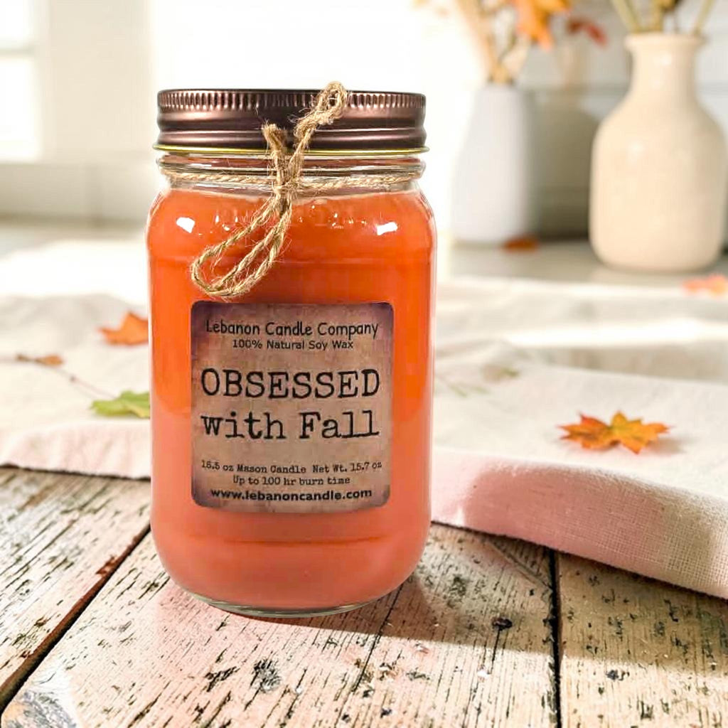 Orange jar candle with twine bow and front label on rustic wood boards