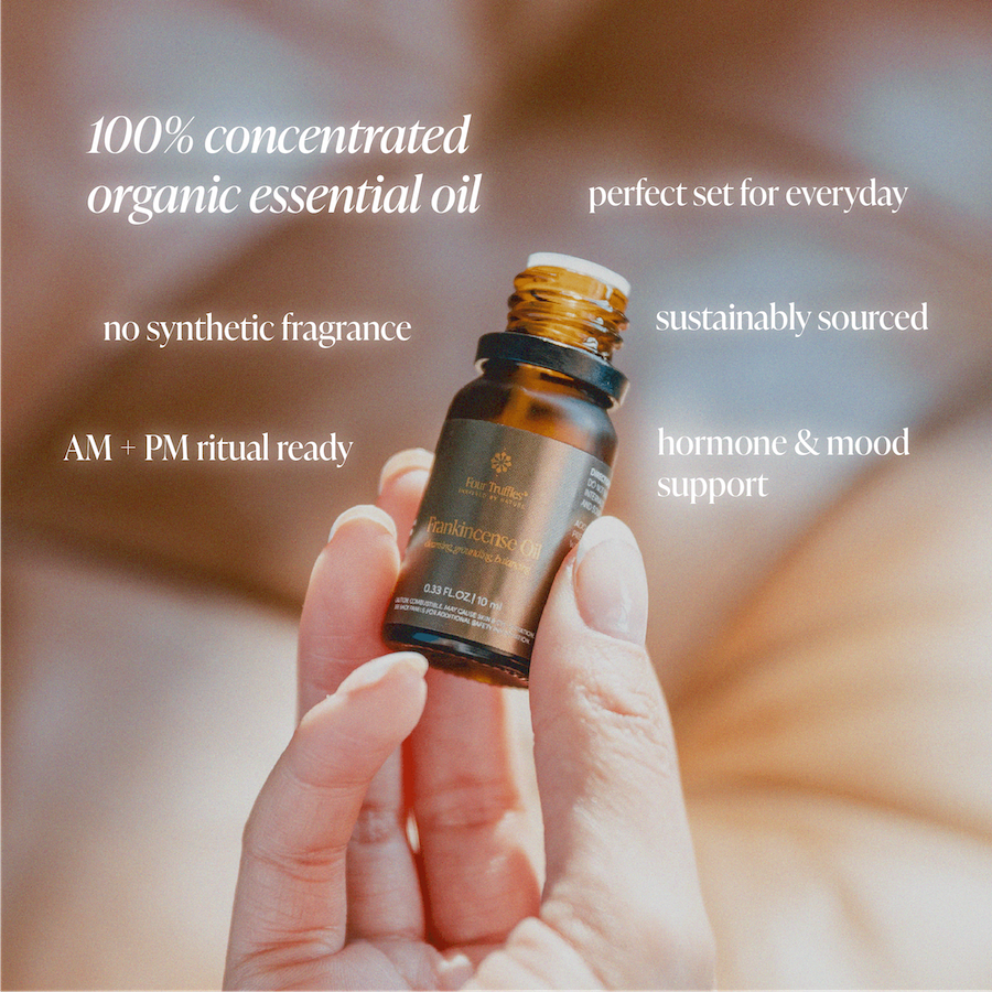 Amber essential oil bottle with black cap held by hand, part of four-oil set